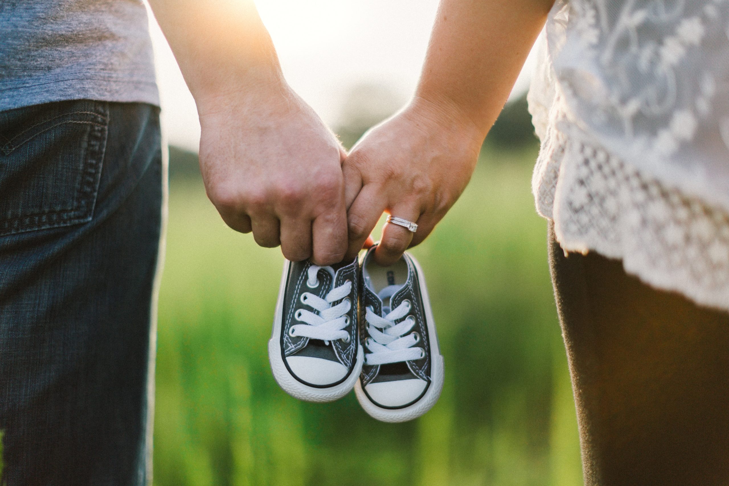 夫婦が手を繋ぎ赤ちゃんの靴を持つ